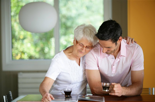 An older adult woman lovingly hugs her son.