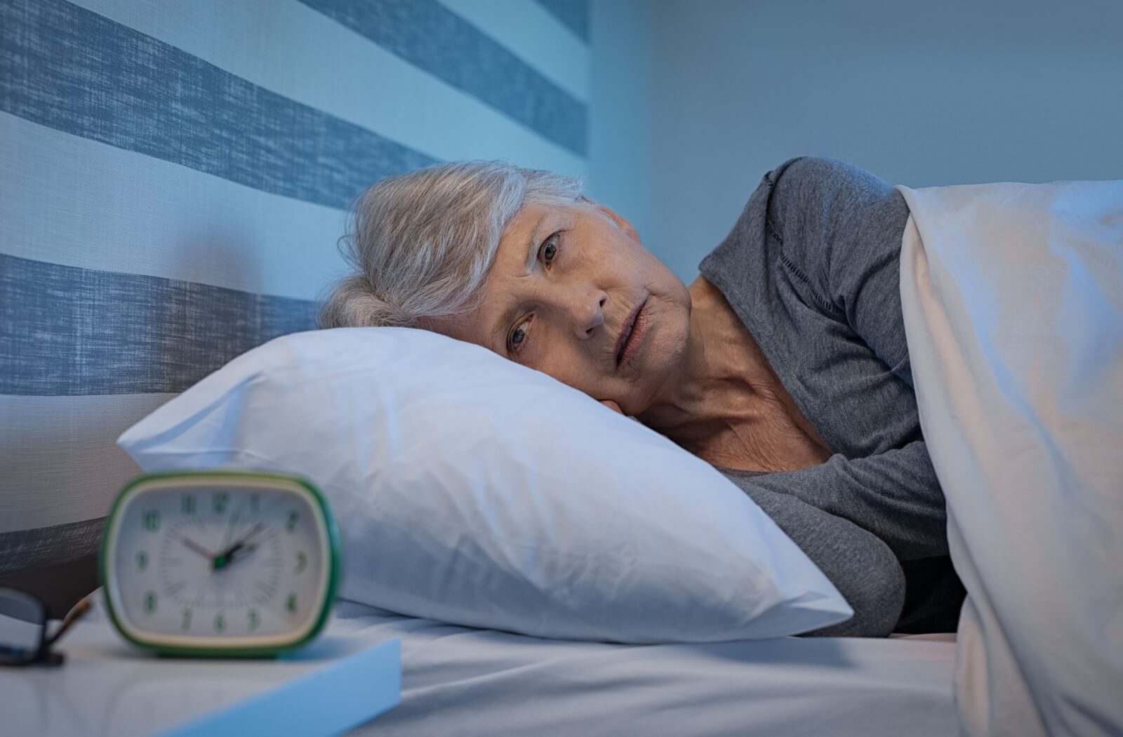 An older adult woman having trouble sleeping, an early sign of dementia.