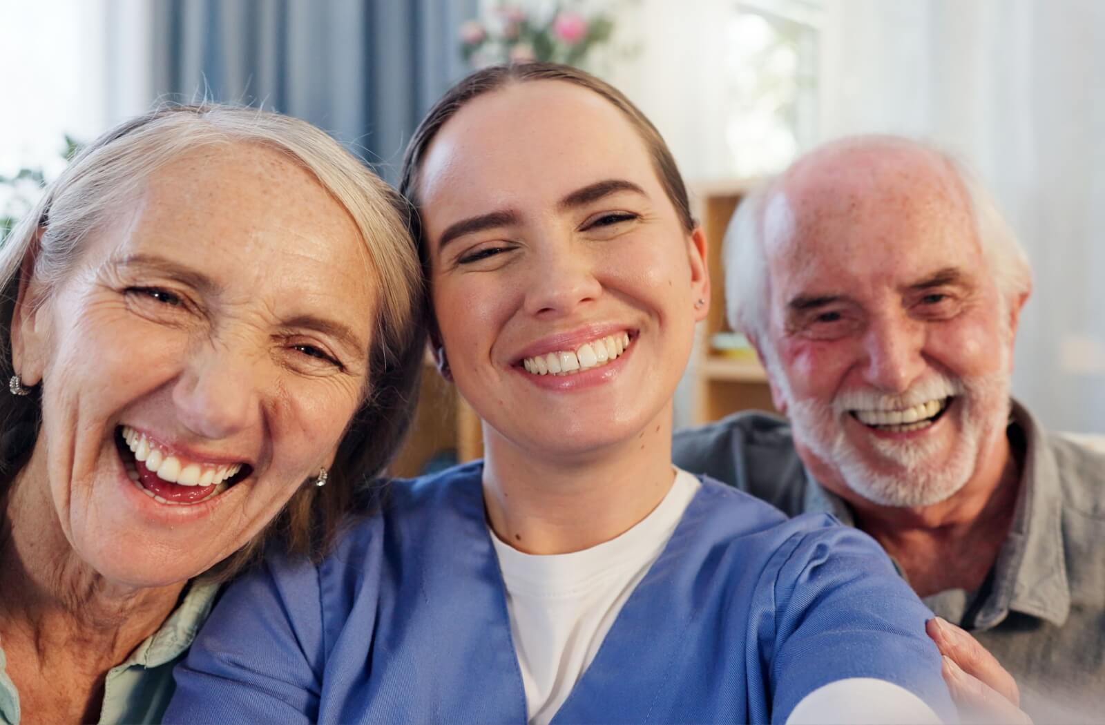 A memory care staff member and two residents smile and take a photo together.