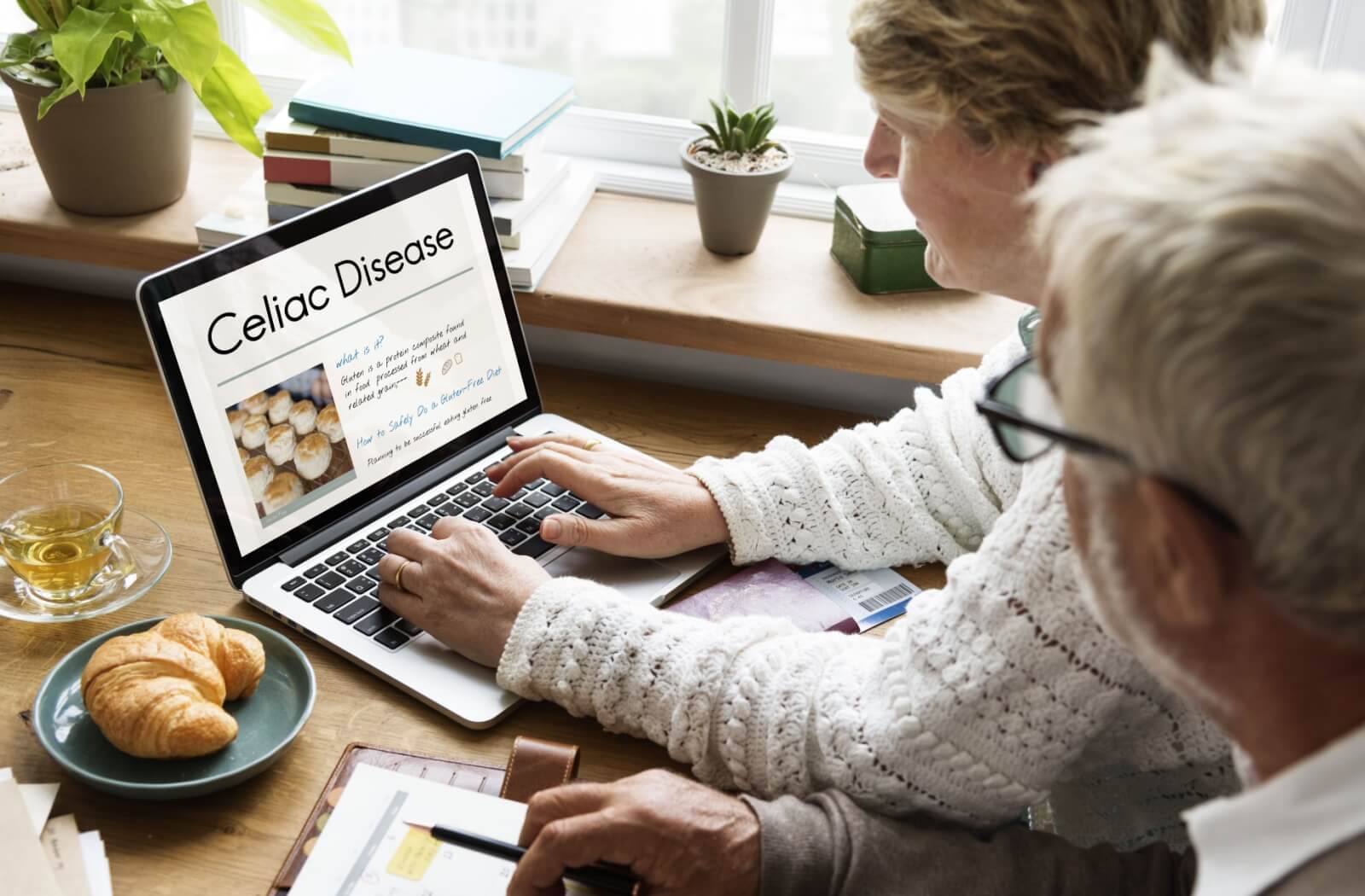 Older adult couple researching Celiac disease on a laptop at home.