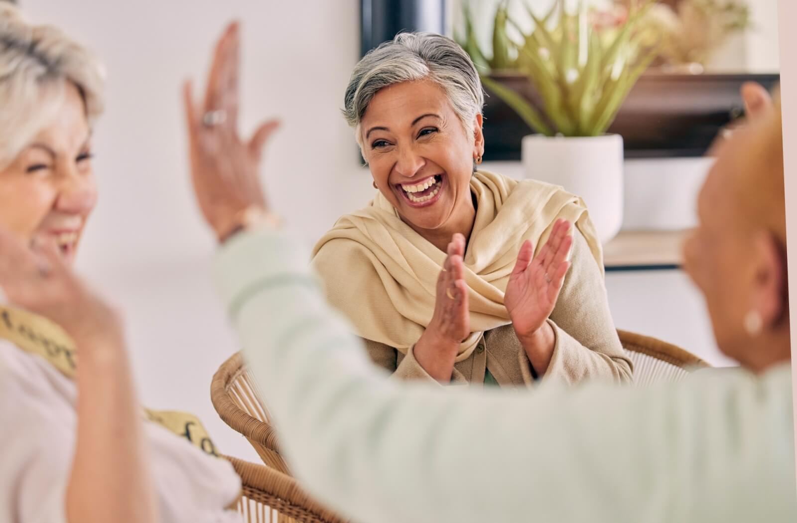 Older adults laughing and enjoying a trivia game together in a care home.